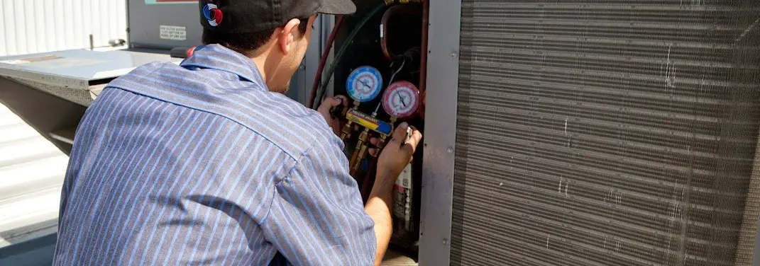 HVAC technician servicing a condenser unit in Hamtramck